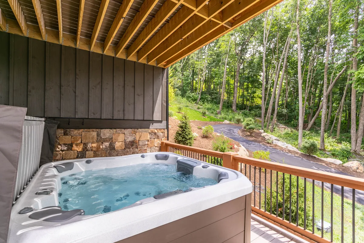 A serene exterior view of a private hot tub nestled on a wooden deck, surrounded by lush greenery. The setting evokes a sense of relaxation and exclusivity, ideal for unwinding after a day of wine tasting or outdoor adventures.