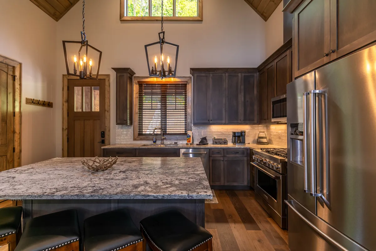 A cozy, inviting kitchen featuring a substantial granite countertop, warm wooden cabinetry, stylish hanging lights, and a central island ideal for meal prep or casual conversations. The setup encourages both culinary creativity and social interaction.