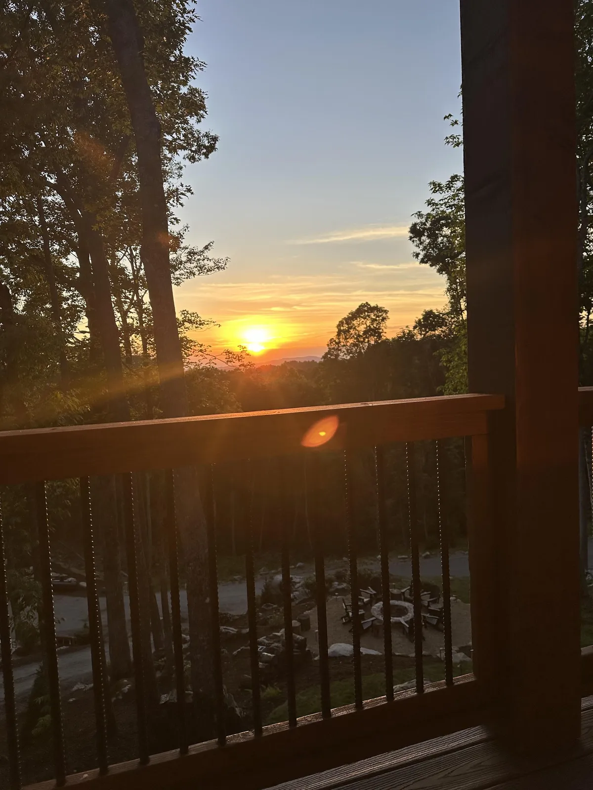 A scenic view featuring a glowing fire pit under a colorful sunset sky, encircled by natural landscape. The ambiance is both romantic and communal, perfect for sharing stories and enjoying the evening after wine tasting.
