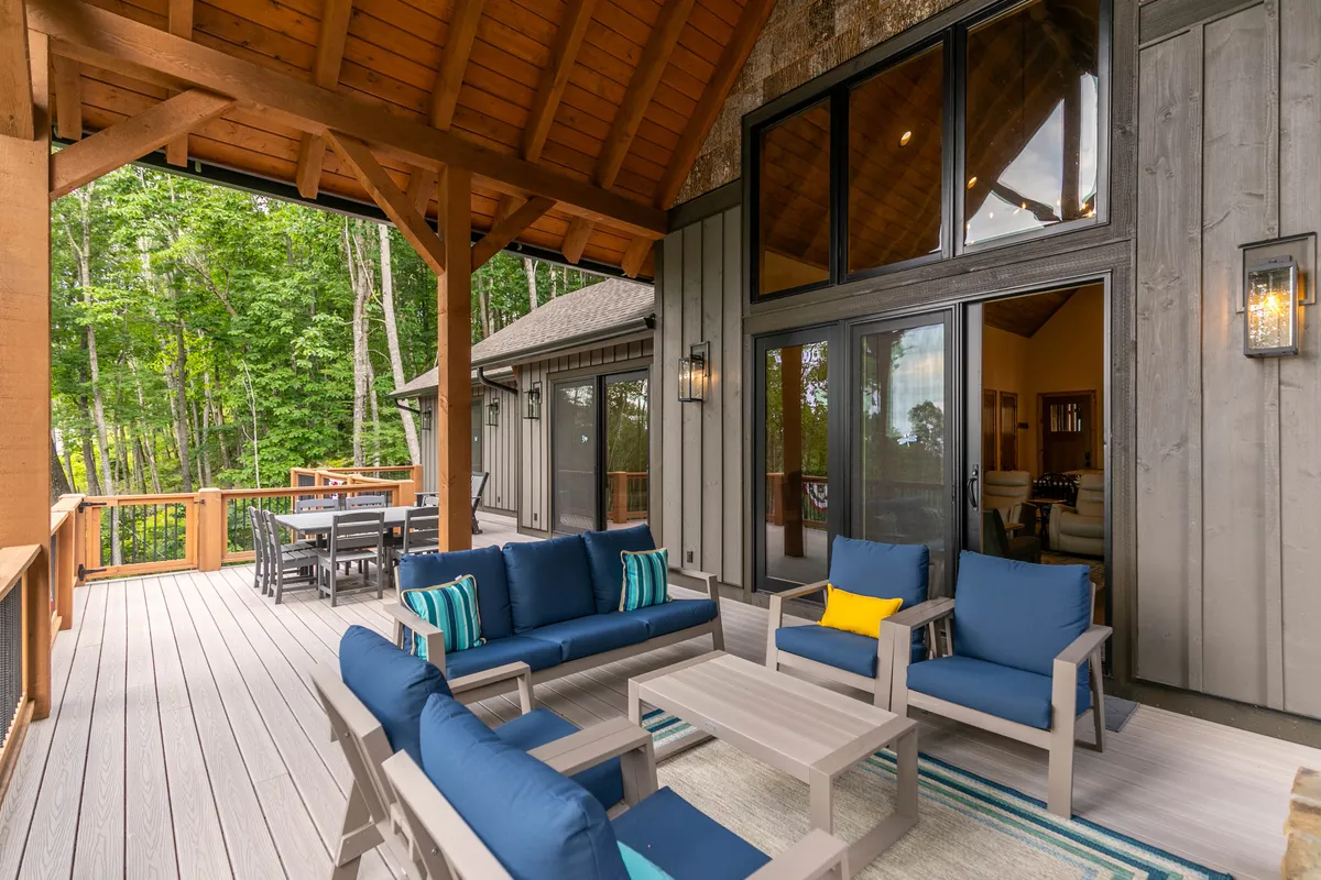 An inviting outdoor seating and dining area set amidst towering trees, with comfortable chairs and a table perfect for sharing local wine and gourmet food. The natural backdrop enhances the feeling of being immersed in the mountain environment.