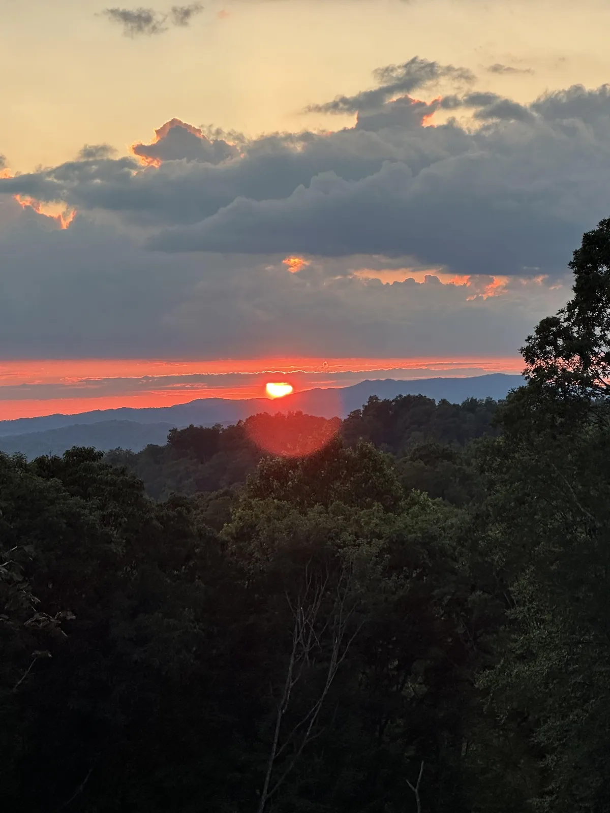 A breathtaking view of a sunset over the mountains with dramatic cloud formations, evoking peace and serenity. The wide-open vista connects the property to its beautiful natural surroundings and emphasizes the sense of escape.